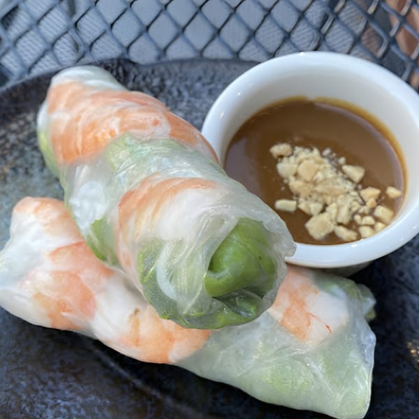 Two fresh Vietnamese spring rolls with shrimp and greens, served with peanut dipping sauce.