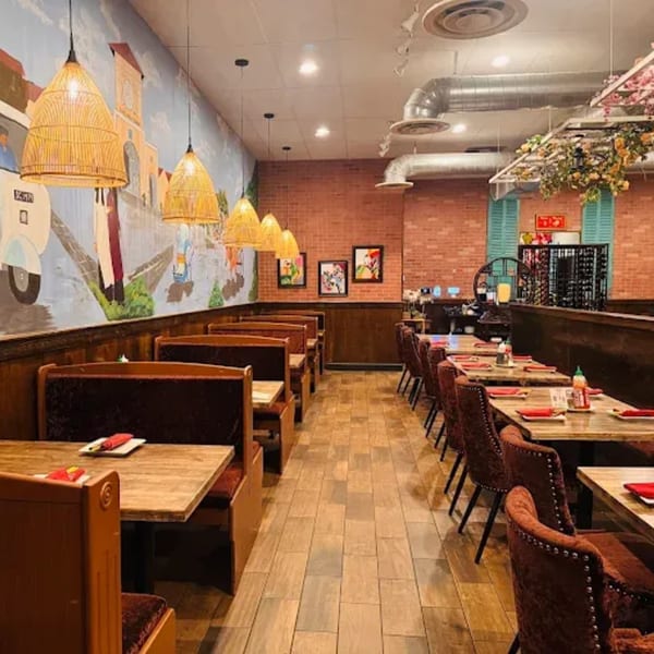 Interior of Viet Chopsticks DC restaurant with booths, tables, chairs, and a mural on the wall.