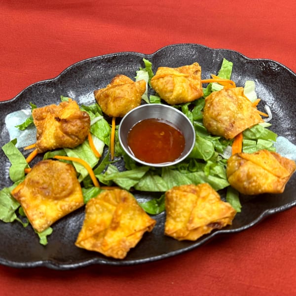 Crispy fried wontons arranged on a bed of lettuce with a side of sweet chili sauce.