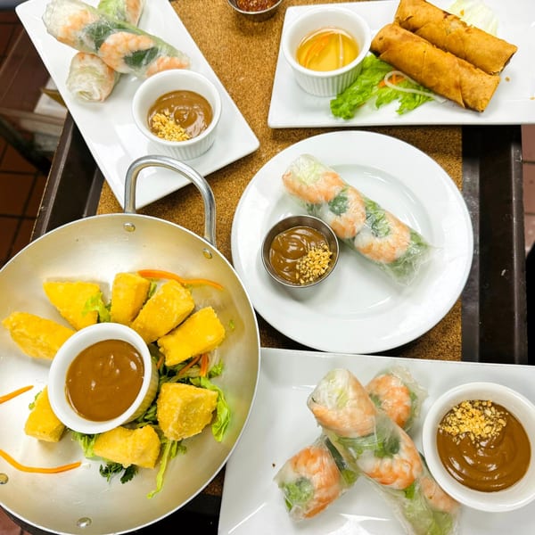 An overhead view of various Vietnamese appetizers, including spring rolls, egg rolls, and fried tofu.