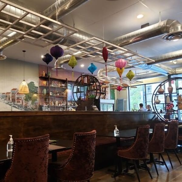 Interior of Viet Chopsticks DC restaurant with colorful lanterns, a bar, and seating with dark chairs.