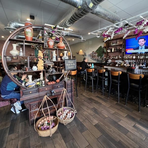 Viet Chopsticks DC restaurant interior with decorative shelving, bar seating, and a "Please Wait To Be Seated" sign.