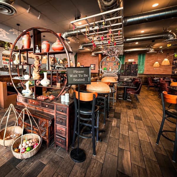Interior of Viet Chopsticks DC Restaurant with decorative shelves, a "Please Wait To Be Seated" sign, and dining tables.