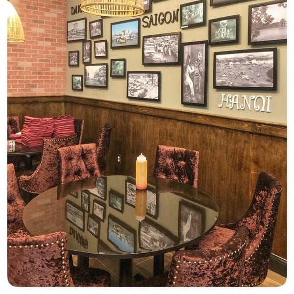 Dining area at Viet Chopsticks DC with velvet chairs, glass tables, and a wall gallery of Vietnamese cityscapes.