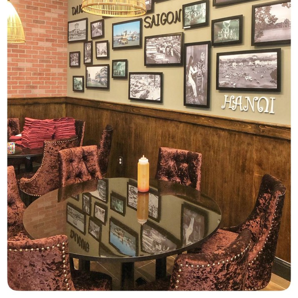 Dining area at Viet Chopsticks DC with velvet chairs, glass tables, and a wall gallery of Vietnamese cityscapes.